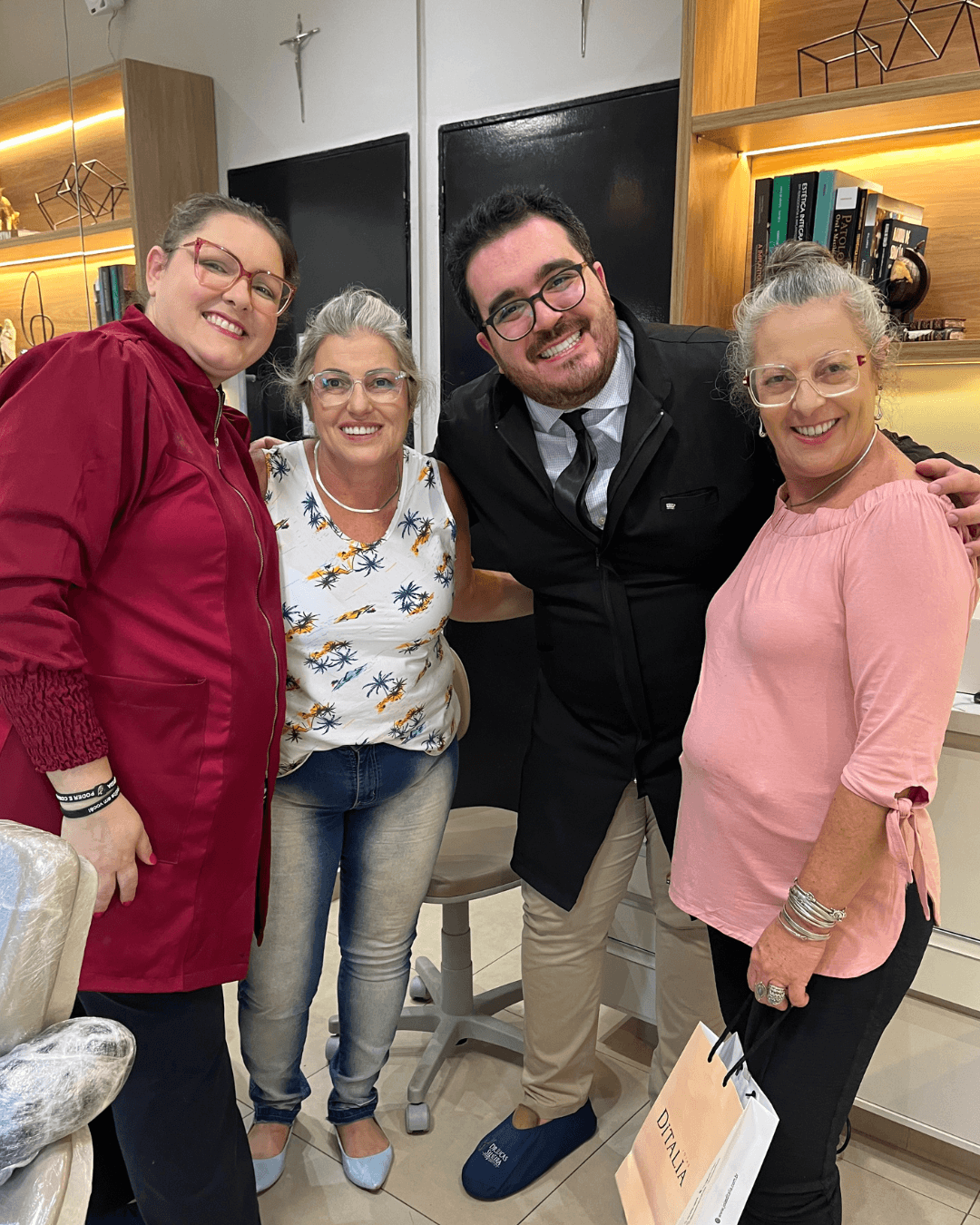 Dois profissionais e duas pacientes sorriem juntos na recepção da Clínica Odontológica Silveira, especialista em implantes em Franca SP.
