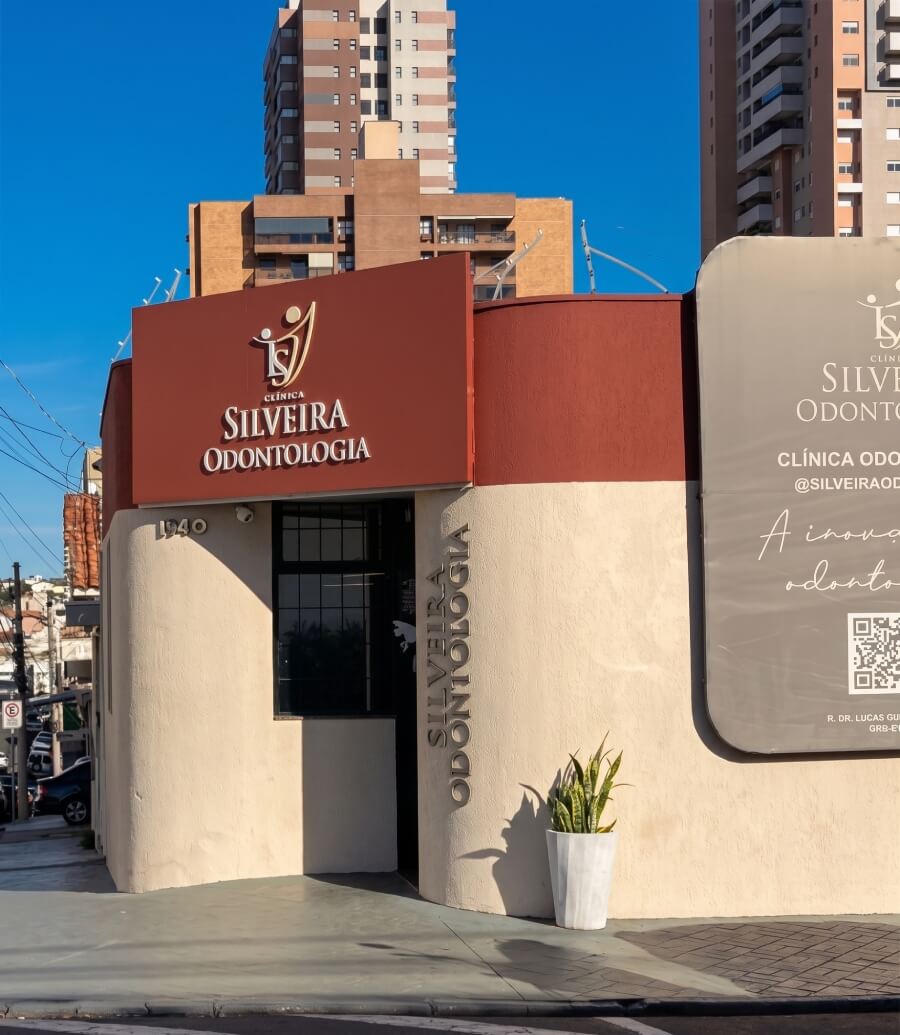 Fachada moderna de esquina da Silveira Odontologia, renomada clínica odontológica com letreiro vinho sob céu azul em Franca SP.