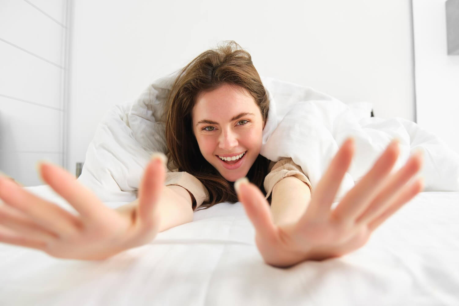 Mulher jovem e sorridente acordando disposta na cama. Saiba como a cirurgia ortognática melhora a respiração em Franca SP.
